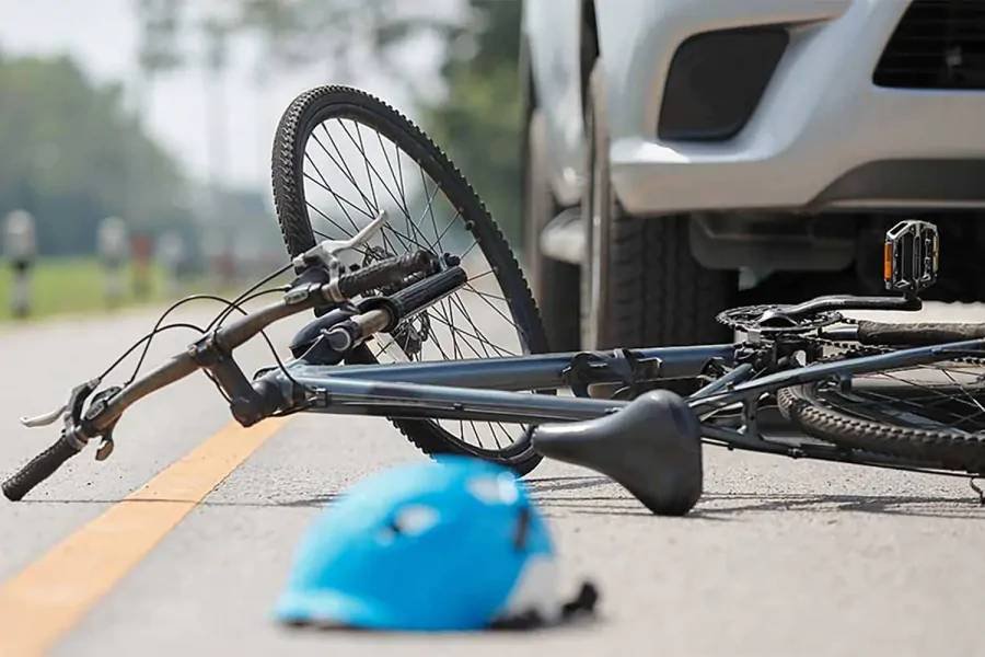 A bicycle on the ground beside a car after a collision